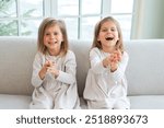 Happy family sisterly love. Two funny little twin sisters girls smiling playing together at home indoors. Happy children lifestyle. Identical twin girls. Girls friendship and youth