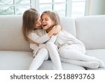 Happy family sisterly love. Two funny little twin sisters girls hugging with love care playing together at home indoors. Happy children lifestyle. Identical twin girls hugs. Girls friendship and youth