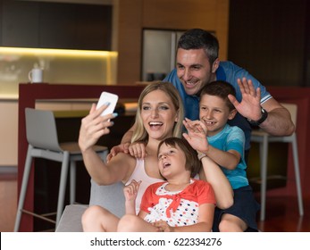 Happy Family Siting On Sofa And Using Cell Phone For Video Call  At Home