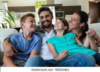 Happy Family Sitting With Arm Around On Sofa At Home