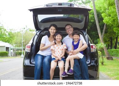 Happy Family Sitting In The Car And Their House Behind