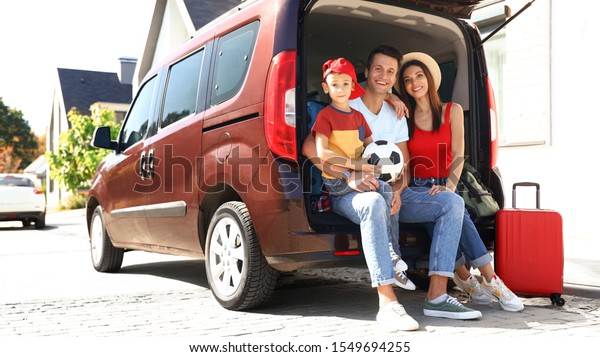 Happy
family sitting in car trunk outdoors. Moving
day