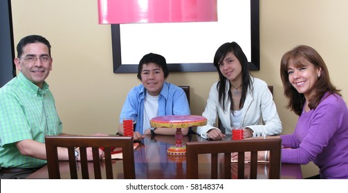 Happy Family Sitting At Dinner Table, Smiling, Looking At The Camera