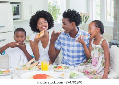 Happy Family Sitting Down To Dinner Together At Home In The Kitchen