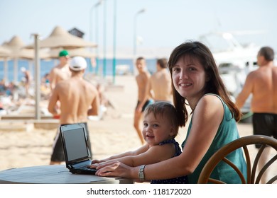 Happy Family  Sitting  With Laptop At Resort Beach