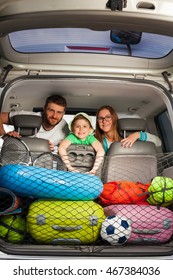 Happy Family Sitting In A Minivan Full Of Luggage