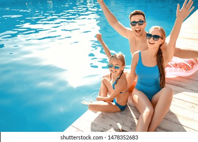 Happy family sitting near swimming pool - Powered by Shutterstock