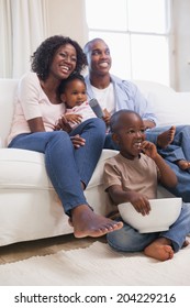 Happy Family Sitting On Couch Together Watching Tv At Home In The Living Room