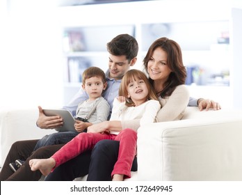 Happy Family Sitting On Sofa In Living Room.