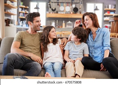 Happy Family Sitting On Sofa In Lounge Talking Together