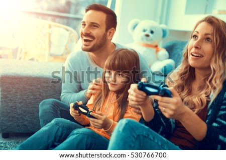 Happy family sitting on a sofa and playing video games.