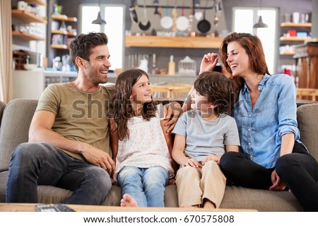 Happy Family Sitting On Sofa In Lounge Talking Together