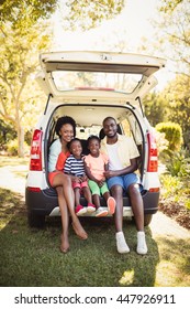 Happy Family Sitting On Their Car At Park