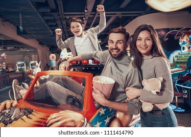 Happy Family Sitting On Toy Car. Rest, Holiday, Leisure. Spending Time Together. Entertainment Center, Mall, Amusement Park.