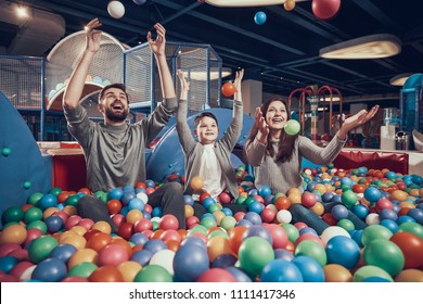 Happy Family Sitting In Pool With Balls. Family Rest, Leisure. Spending Holiday Together. Entertainment Center, Mall, Amusement Park.