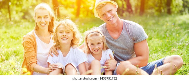 Glückliche Familie sitzt zusammen auf einer Wiese