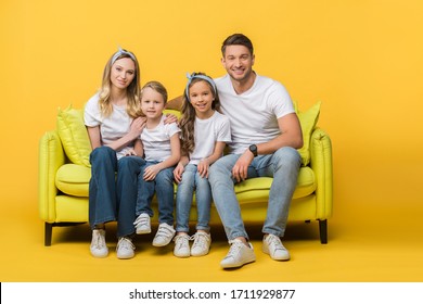 Happy Family Sitting Together On Sofa On Yellow