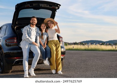 Happy family sitting in trunk of car outdoors, space for text - Powered by Shutterstock