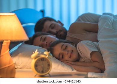 The happy family sleeping in the comfortable bed. night time