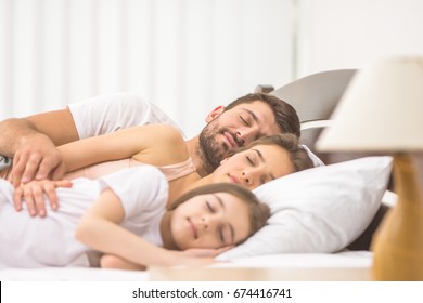 The happy family sleeping on the comfortable bed