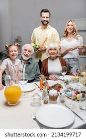 Happy Family Smiling At Camera Near Table Served With Easter Dinner