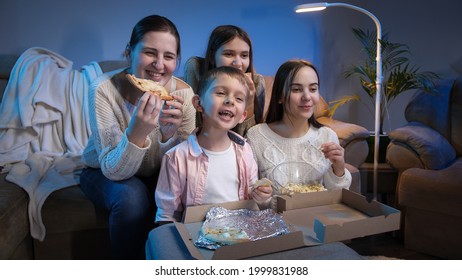 Happy Family Smiling And Laughing While Eating Pizza And Watching TV Movie Or Show At Night.