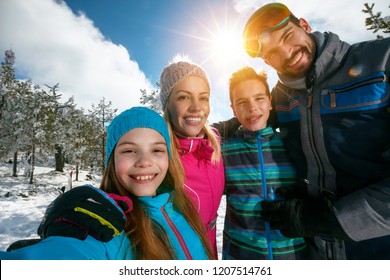 Happy Family Smiling And Making Selfie On Winter Ski Vacation