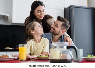 Happy Family Smiling Near Breakfast In Kitchen On Blurred Foreground