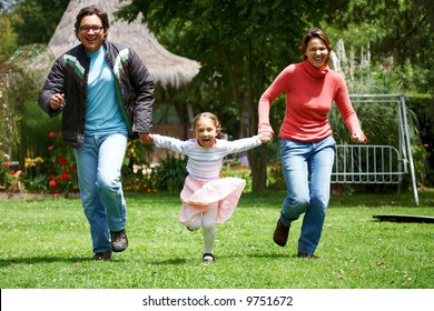 Happy Family Smiling And Running Outdoors Towards The Camera