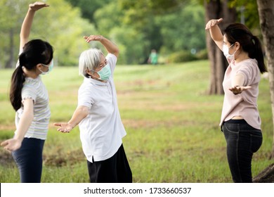 Happy Family Smiling While Exercising At Outdoor Park,mother,daughter And Healthy Grandmother Are Stretching Arm Workout,wearing Surgical Mask,enjoy,relaxation After Coronavirus Quarantine Or Covid-19