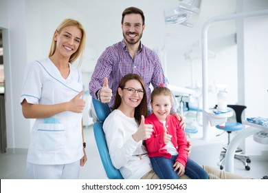 Happy Family With A Smiling Young Dentist In A Dental Office