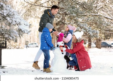 Happy Family With Snowman In Winter Park