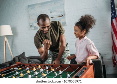 Happy Family Of Soldier Father And African American Daughter Playing Table Football