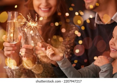 Happy family with sparklers and champagne celebrating Christmas at home - Powered by Shutterstock