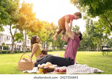 happy family spending time on summer day. Father lifted son into the air while picnicking in the park on a summer day - Powered by Shutterstock