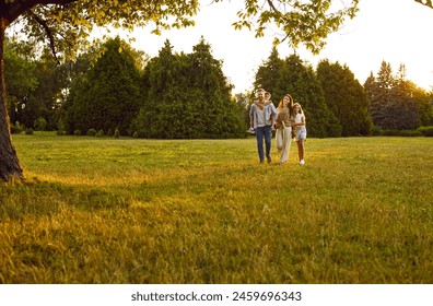 Happy family spending time outdoors. Parents and kids strolling in nature. Mother, father and children enjoying quiet summer evening and walking together on green lawn in beautiful city park or garden - Powered by Shutterstock