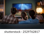 Happy family spending time together. Mother, father and child watching  TV, movies in the evening at home.