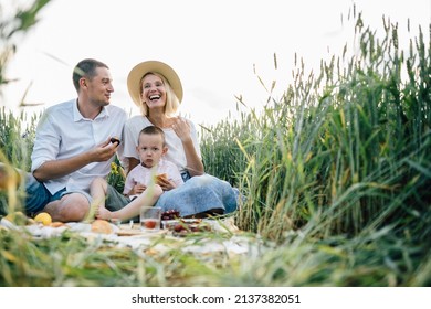 Happy family spending time together outside in nature on vacation outdoors. Mom, dad and son sitting on weat field at nature countryside. The concept of family holiday.