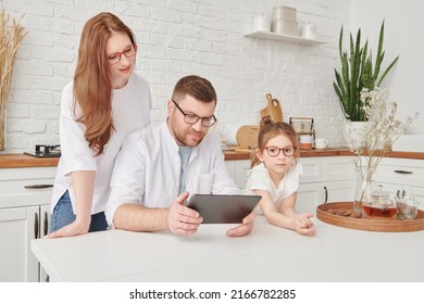 Happy Family Spending Time Together At A Table In The Sunny Kitchen With An Ipad Tablet. Kitchen Design, Furniture For Kitchen. Amicable, Happy Family.