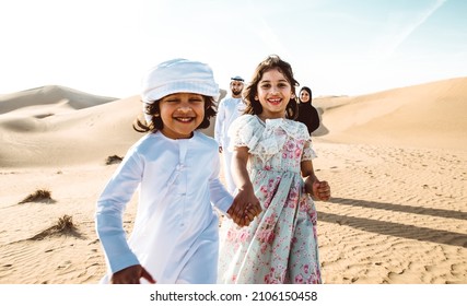 Happy family spending a wonderful day in the desert making a picnic. People from the emirates with traditional clothes making a safari in Dubai