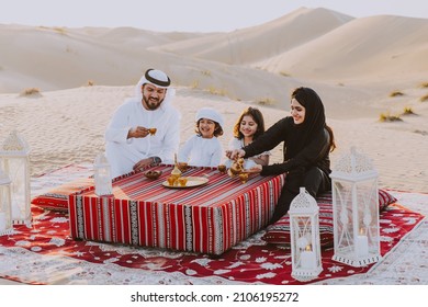 Happy family spending a wonderful day in the desert making a picnic. People from the emirates with traditional clothes making a safari in Dubai - Shutterstock ID 2106195272