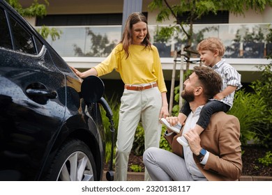 Happy family standing beside their car and charging electric car on the street. - Powered by Shutterstock