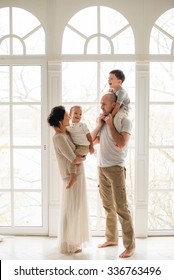 Happy Family Standing By The Window Of A Beautiful New Home