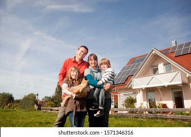 Happy family standing in front of house with solar panels