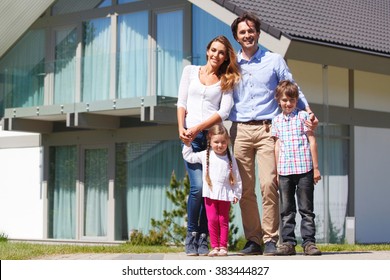 Happy Family Standing In Front Of The House