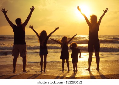 Happy family standing on the beach on the dawn time - Powered by Shutterstock