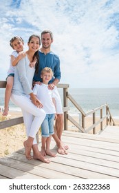 Happy Family  Standing On A Wood Pontoon In Front Of The Sea In Summertime