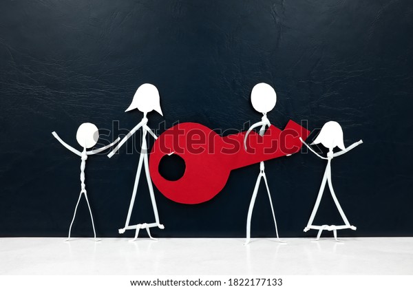 Happy family stick figure carrying\
together a big red key in dark background with copy space. Buying\
and owning a new house, car or property\
concept.