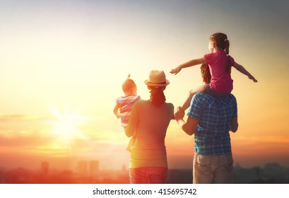 happy family at sunset. father, mother and two children daughters having fun and playing in nature. the child sits on the shoulders of his father. - Powered by Shutterstock