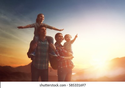 Happy family at sunset. Father, mother and two children daughters having fun and enjoying journey. The kid sits on the shoulders of his dad.